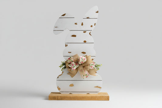 Wooden bunny decoration with a floral bow on a wooden surface.